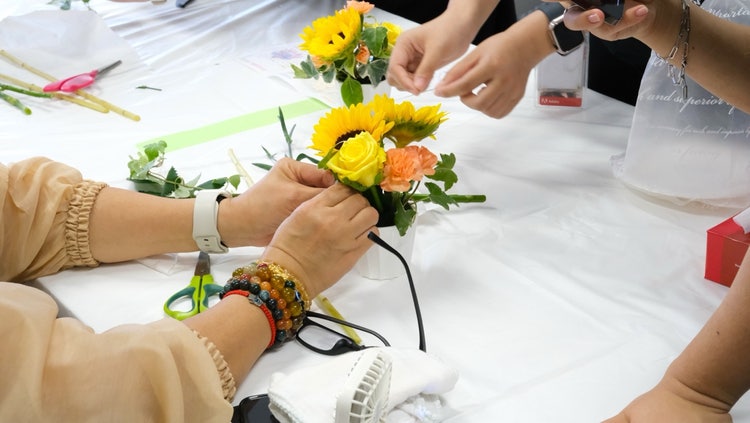 テーブルの上で花材を選びながら、ミニフラワーアレンジメントを制作しているワークショップの様子