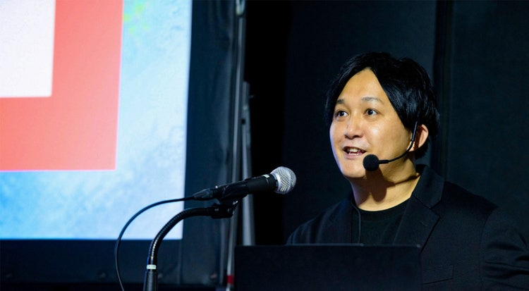 モニターの前に立っている女性 中程度の精度で自動的に生成された説明