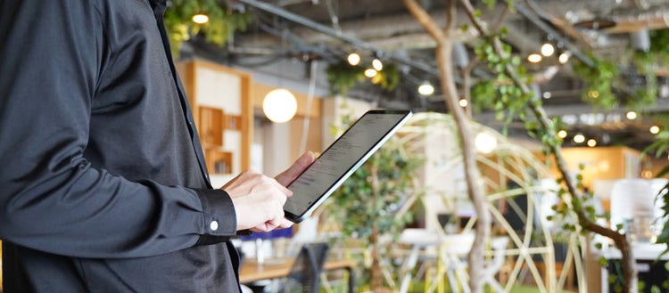 カフェ店内でタブレットを操作する人物のイメージ写真