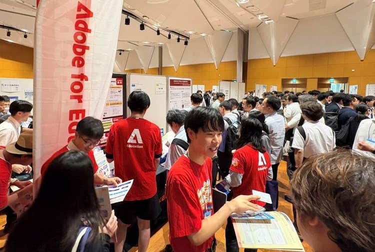 来場者にフライヤーなどを配ってAdobe Expressをアピールする山田先生（写真中央）