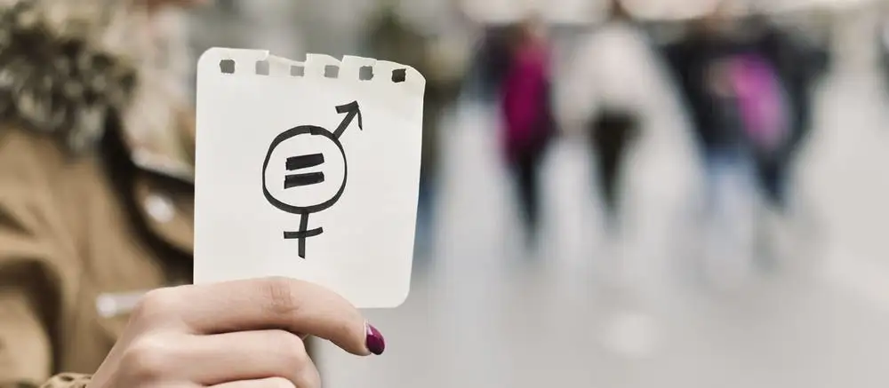 남성과 여성을 상징하는 기호와 함께 동등하다는 '=' 표시를 한 메모를 들고 있는 여성